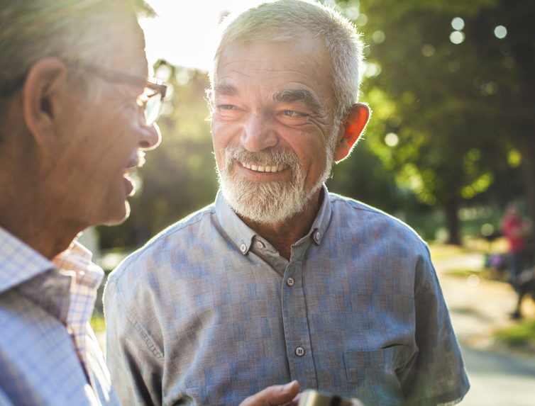 Two older gentleman chatting in the sunshine.